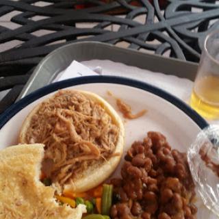 A delicious meal featuring pulled pork, beans, cornbread, and assorted vegetables.