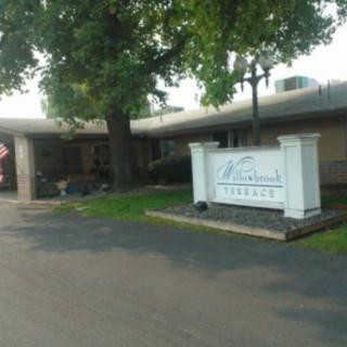 Entrance of a building with a white sign and surrounding trees.