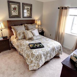A cozy bedroom with a neatly made bed, soft lighting, and decorative artwork.
