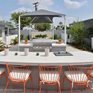 Modern outdoor patio with seating and barbecue area under a shade canopy.