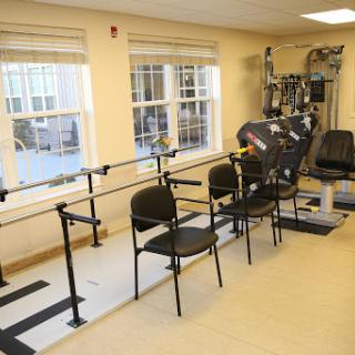 A well-equipped rehabilitation therapy room featuring exercise bars and chairs.