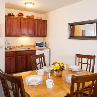 A cozy kitchen and dining area with a wooden table set for four, featuring a microwave and cabinets.