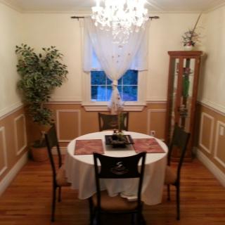 A cozy dining room with a round table and elegant chandelier lighting.