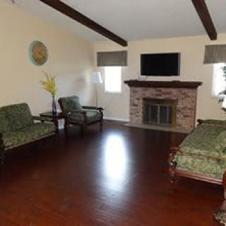 A cozy living room with wooden floors, featuring a fireplace and seating area.