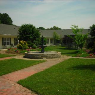 A landscaped courtyard featuring a central fountain, surrounded by well-maintained lawns and garden pathways.