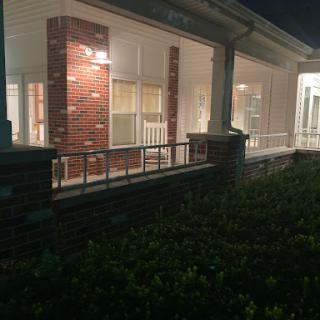 A well-lit residential building captured at night, showcasing its architectural features and surrounding greenery.