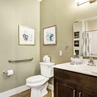 A modern bathroom with a toilet, sink, mirror, and artwork on the walls.