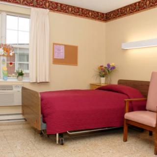 A neat and simple hospital room with a single bed, chair, and window.