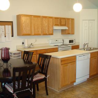 A kitchen with wooden cabinets, a dining table, and modern appliances.