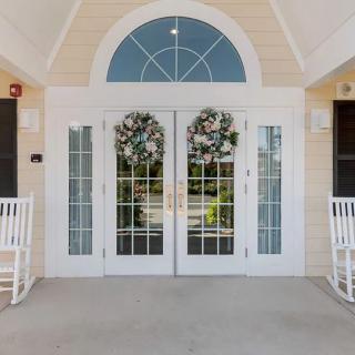 A welcoming entrance with white double doors adorned with wreaths and flanked by rocking chairs.