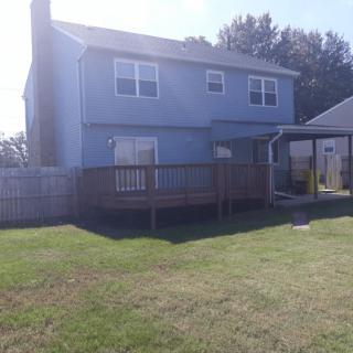A two-story house with a wooden deck and fenced backyard.