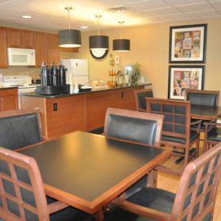A modern dining area with wooden furniture and kitchen appliances in the background.