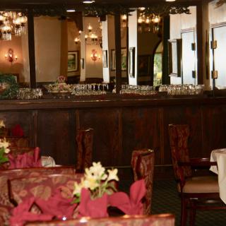 A cozy restaurant interior with elegantly set tables and warm lighting.