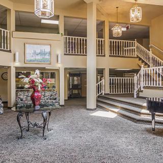 A spacious lobby featuring a grand staircase and elegant chandeliers.