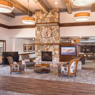 A cozy living room with a stone fireplace and rustic wooden beams.