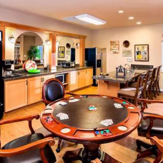 A well-furnished game room featuring a poker table and kitchenette.