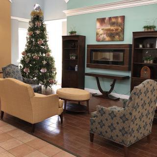 A cozy living room decorated for the holiday season with a Christmas tree, comfortable seating, and a fireplace.