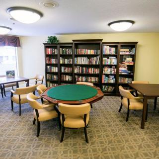 A cozy library space featuring bookshelves, tables, and chairs.