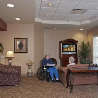 An elderly care facility living room with residents watching television.