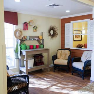 A cozy living room with armchairs and decorative shelves, featuring hats and plants.