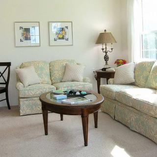 A cozy living room featuring a comfortable sofa, a wooden coffee table, and framed artwork on the wall.