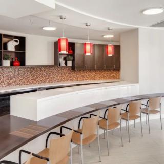 A modern kitchen with a curved seating area, featuring red pendant lights and sleek design elements.