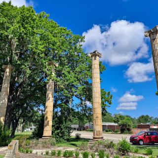 Remnants of ancient architecture, standing tall against a backdrop of blue sky and lush greenery.