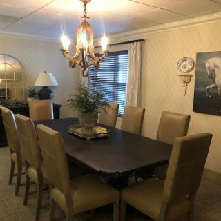 A well-appointed dining room featuring a large table with eight chairs and an elegant chandelier.