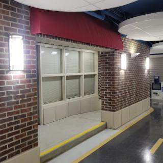 A view of a well-lit corridor featuring a brick wall and a window with steps leading up to it.