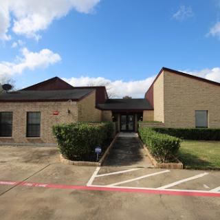 A well-designed building with a landscaped entrance under a bright blue sky.