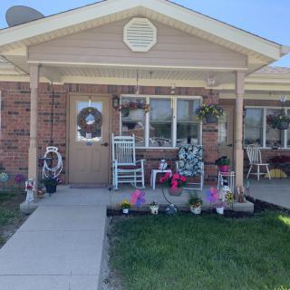 A cozy house with a welcoming porch adorned with flowers and a rocking chair.