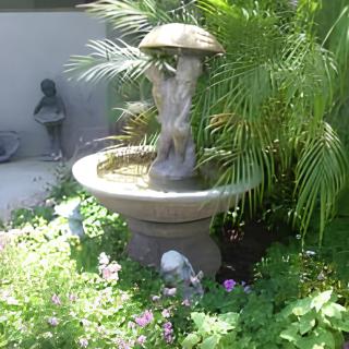 A garden fountain with a sculpture surrounded by lush greenery.