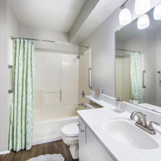 A modern bathroom with a large mirror, sink, and shower area.