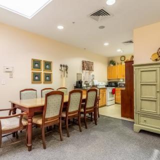 A cozy dining area connected to a kitchen, featuring a wooden table with chairs and a cabinet.
