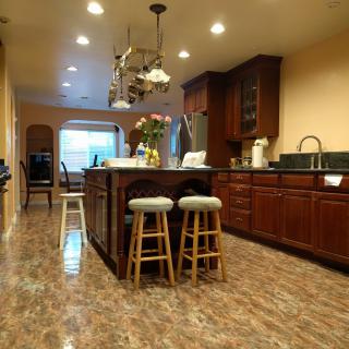 A spacious kitchen featuring an island with bar stools, wood cabinetry, and a chandelier.