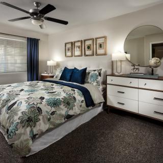 A modern bedroom with floral bedding and a stylish dresser.