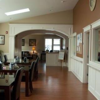 A cozy dining area with wooden tables and chairs, accented by warm lighting and wood flooring.