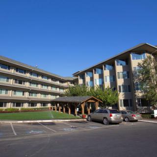 A modern apartment building with a parking lot on a clear, sunny day.