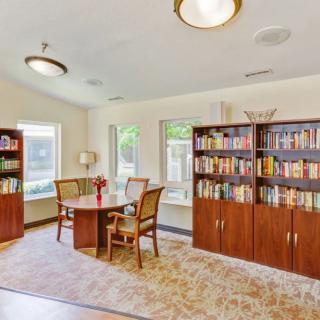 A cozy library space with bookshelves, a reading table, and chairs by the windows.