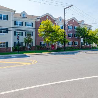 A view of a residential apartment building along a quiet street lined with trees.