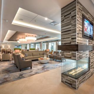A modern lounge interior featuring a fireplace, comfortable seating, and a chandelier.