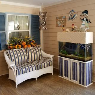 A cozy living room interior featuring a striped sofa and an aquarium with nautical-themed decorations.