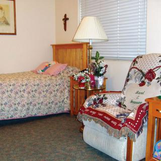 Cozy bedroom with a bed, lamp, and chair featuring decorative elements.