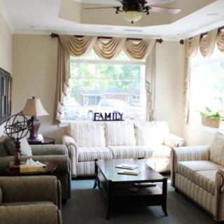 A cozy living room with a sofa set, coffee table, and large windows with elegant curtains.