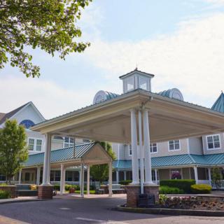 A front view of a large building with a covered entrance and landscaped surroundings.
