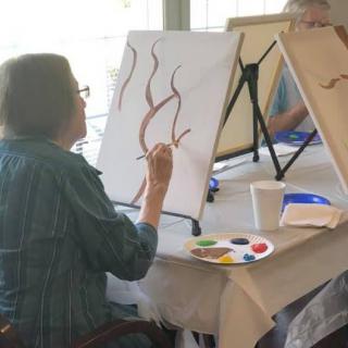 A person engaged in painting during an art class session.