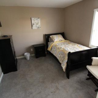 A cozy bedroom with a single bed, nightstand, and dresser featuring neutral tones.