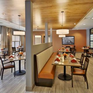 A well-lit restaurant dining area with tables and booth seating, featuring modern decor and warm lighting.