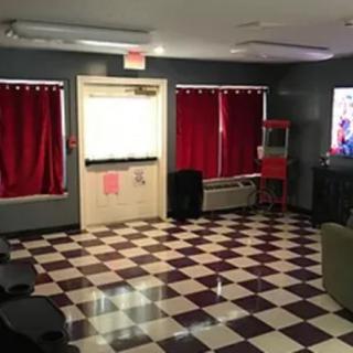 A cozy lounge area with a checkered floor, featuring red curtains, a popcorn machine, and a television.