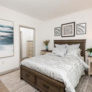 A modern bedroom with a neatly made bed, stylish decor, and artwork on the walls.